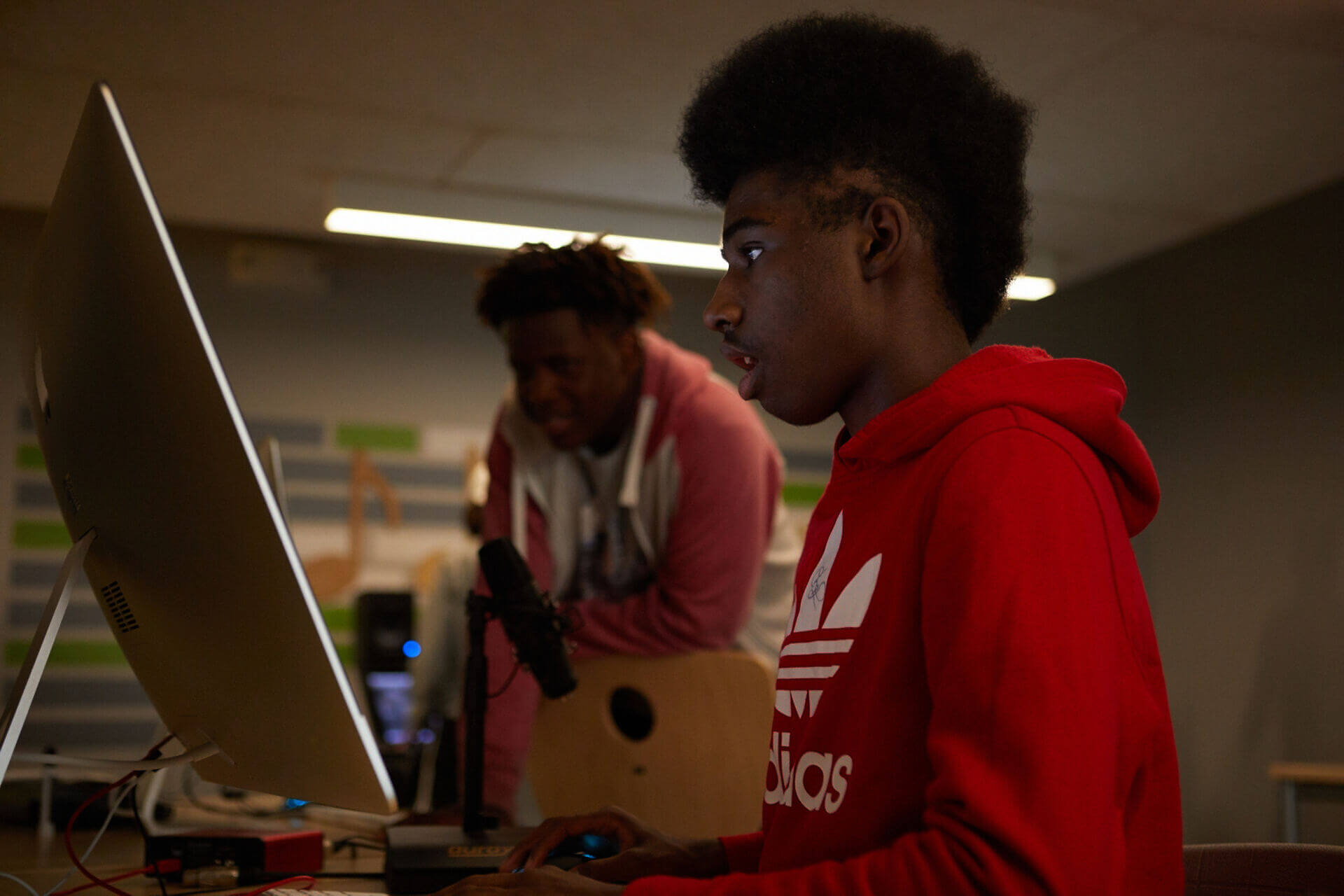 young male student with a red hoodie working on a computer