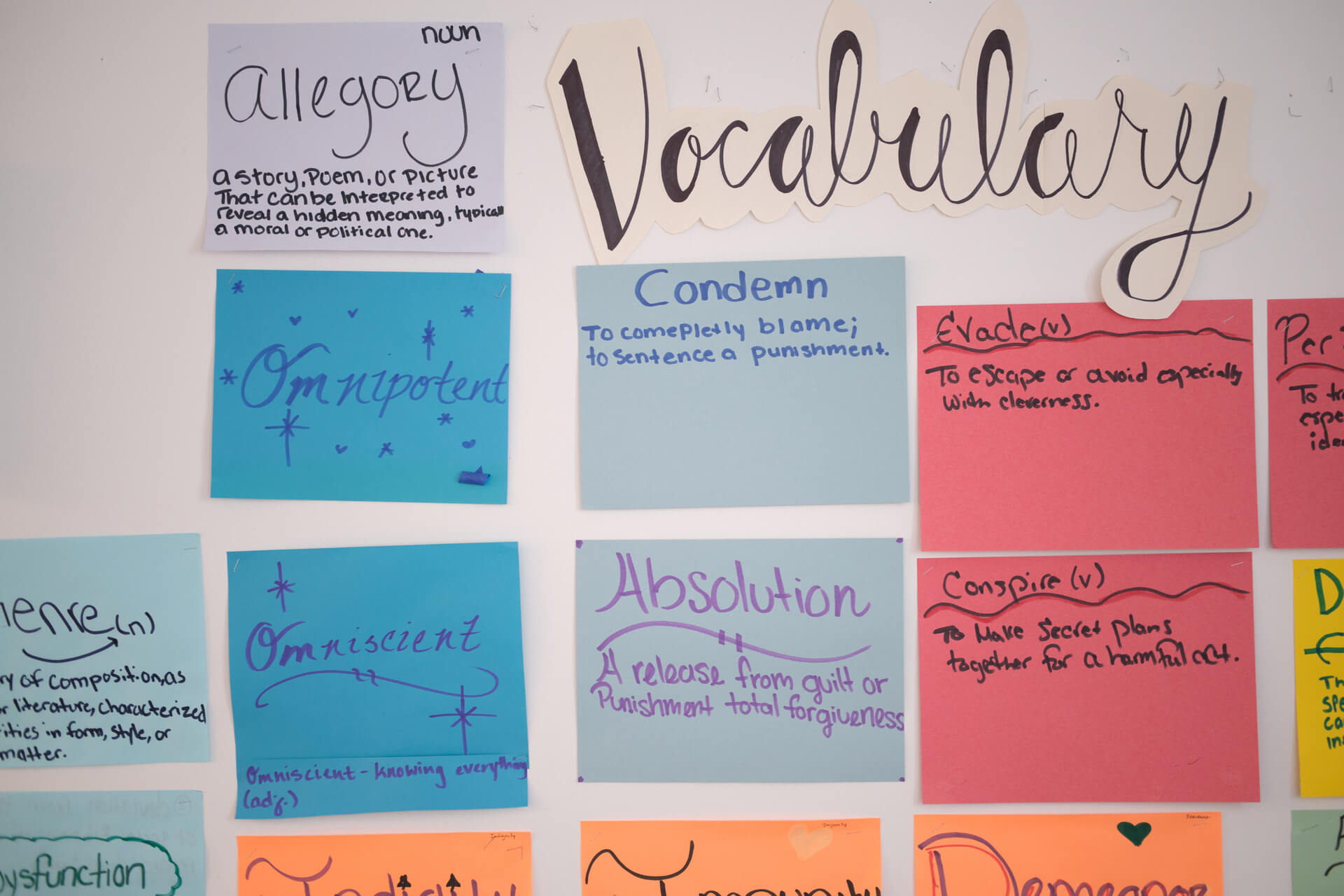 A whiteboard in a classroom with vocabulary words listed on colorful post-it notes.